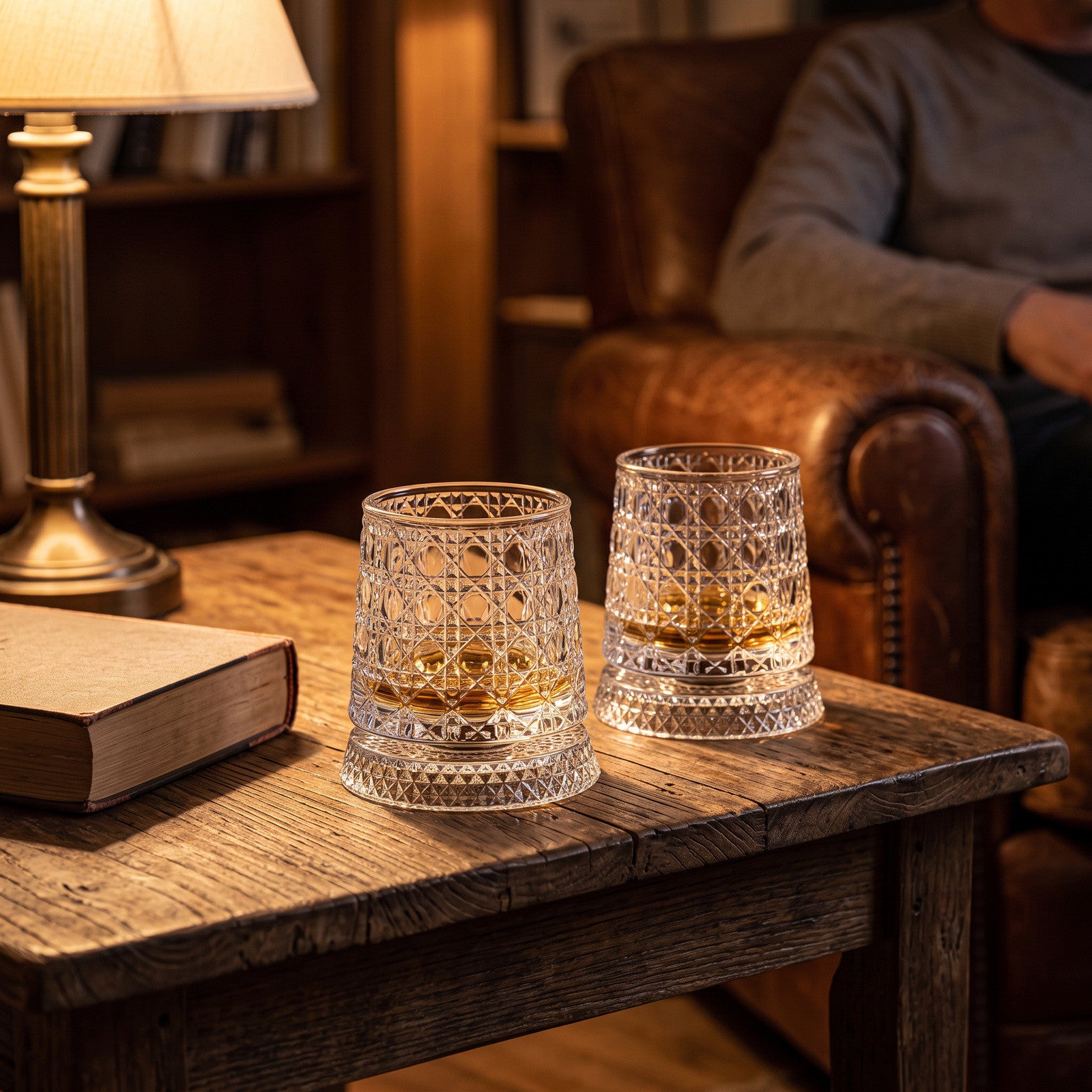 Two scallop glasses beside a closed novel and lamp